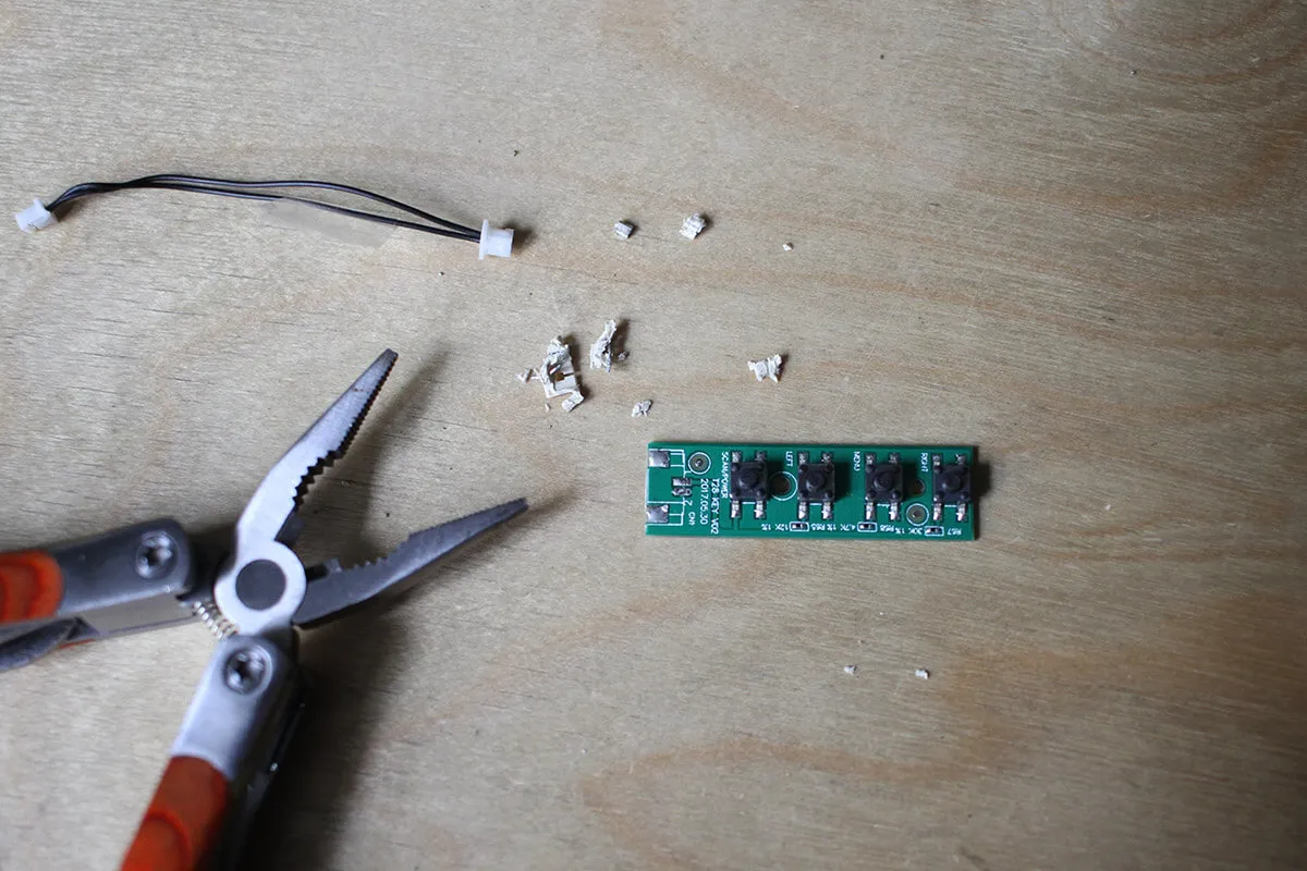 The control buttons circuit with connector removed next to pliers.